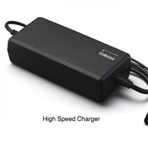 En Yamaha-laddare för City, Curve, Mini, Slim och Carve Mountainbikes är på en vit yta, med strömkablar snyggt anslutna. Texten "High Speed Charger" indikerar dess effektivitet när det gäller att hålla din familjecykel redo för äventyr.