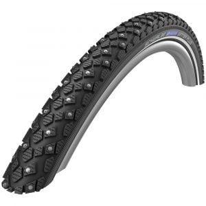 Närbild av ett svart däck med metalldubbar på slitbanan för förbättrad grepp, designat för Curve E, City E, Mini E och alla lastcyklar av Mountainmodeller. Sidoväggen visar varumärke och produktspecifikationer. Däcket är placerat mot en vanlig vit bakgrund.