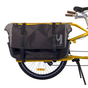 Närbild av bakdelen av en gul lastcykel, med en stor svart Go-Getter-packväska med två spännremmar och en vit Yuba-logotyp, säkert fäst över bakhjulet för extra förvaring.