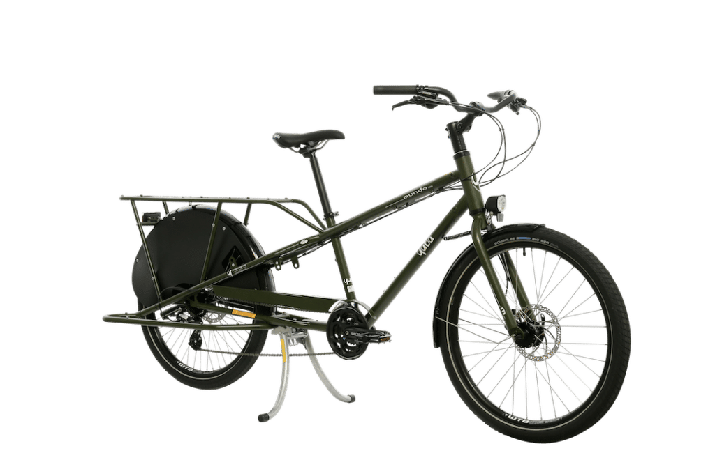Bilden visar en grön Yuba Mundo Lux lastcykel med förlängd pakethållare för transport av tunga laster eller passagerare, upprättstående styre för bekväm körning och dubbla cykelstöd för extra stabilitet.