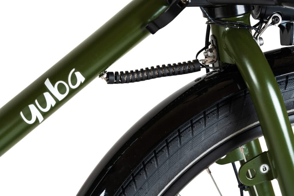 Närbild av en grön ram på en Yuba Mundo Lux ellastcykel med den vita Yuba-logotypen, som visar framhjulet och den svarta styrstabilisatorfjädern som förbinder gaffeln med ramen, allt mot en vit bakgrund.