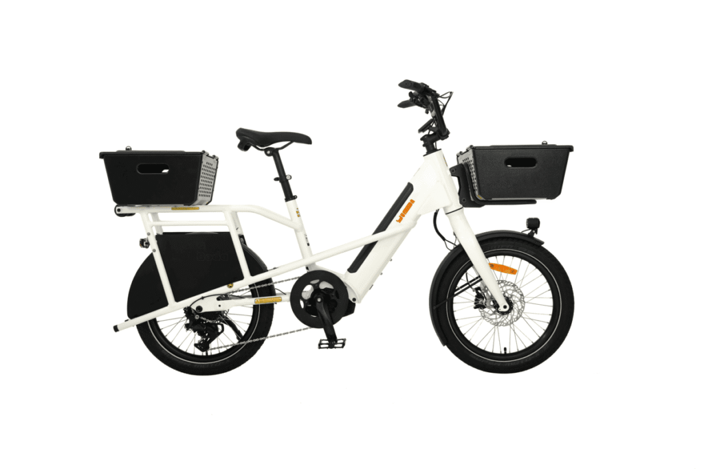 Vit Yuba Mini Boda Boda elektrisk lastcykel med svart pakethållare bak och korg fram, med stora svarta behållare, vy från sidan.