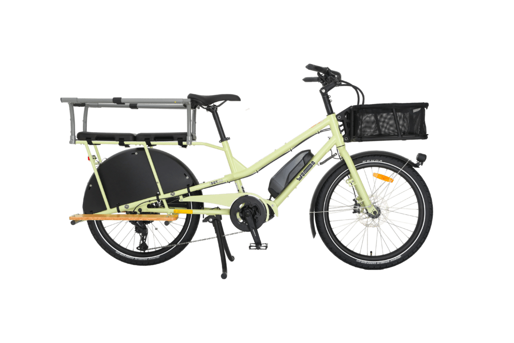 En gul Yuba Kombi EP5, en eldriven lastcykel med ett långt bakre pakethållare, svart hjulskydd, sidostöd och framkorg, avbildas i profil mot en vit bakgrund.