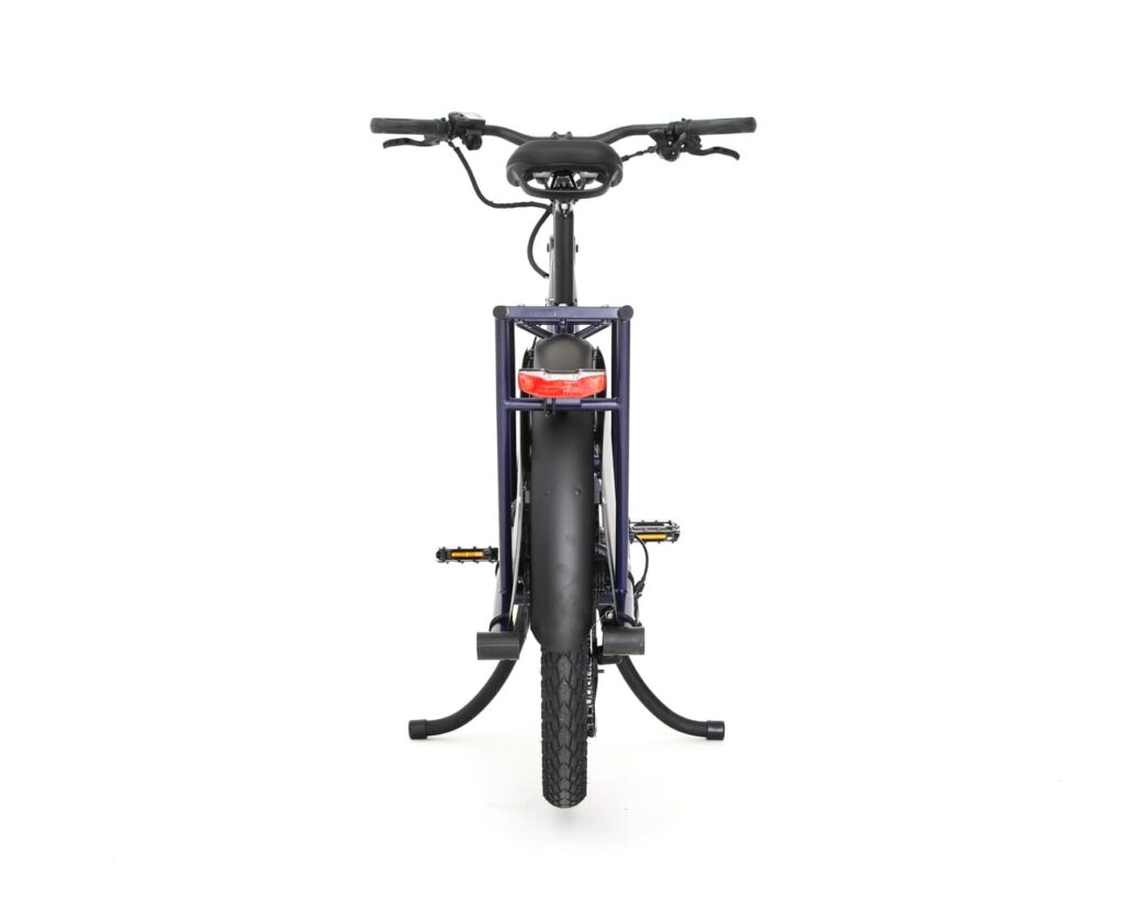 Framifrånbild av lastcykeln Yuba Kombi EP5 mot en vit bakgrund, där man ser styret, framhjulet, pedalerna, strålkastaren och ett stöd som håller cykeln i upprätt läge.