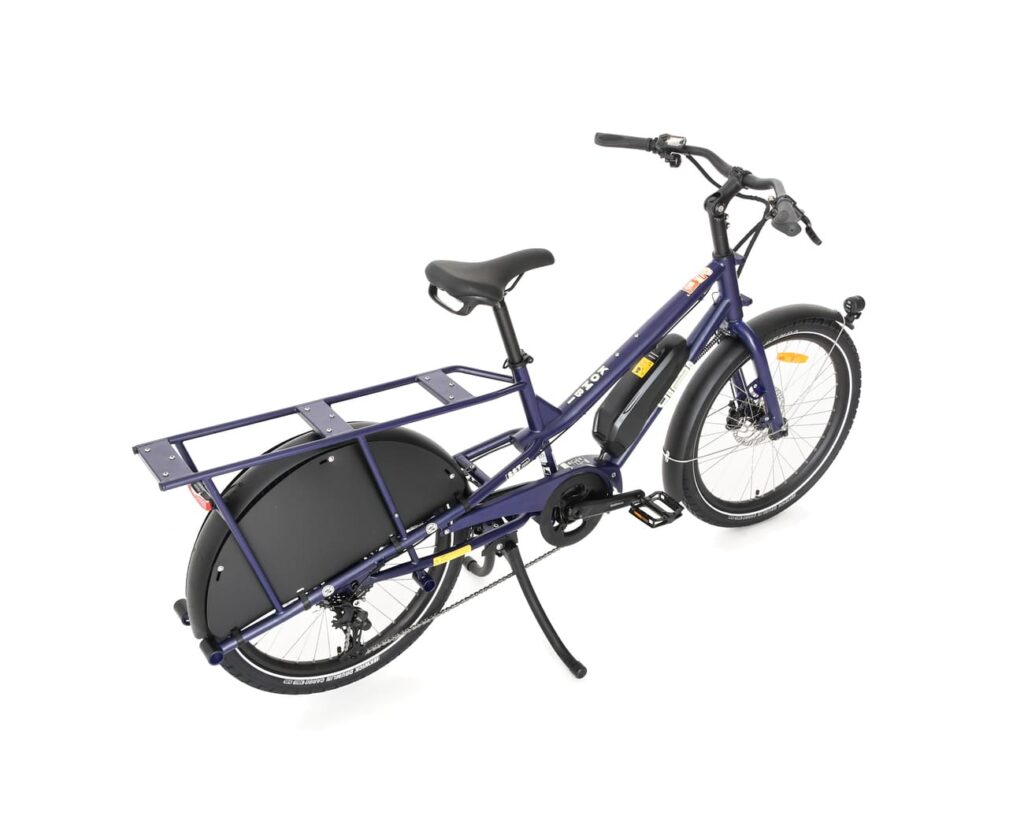 En mörkblå Yuba Kombi EP5, en eldriven lastcykel med ett robust bakre pakethållare, svarta stänkskärmar och ett stöd, avbildad mot en vit bakgrund.