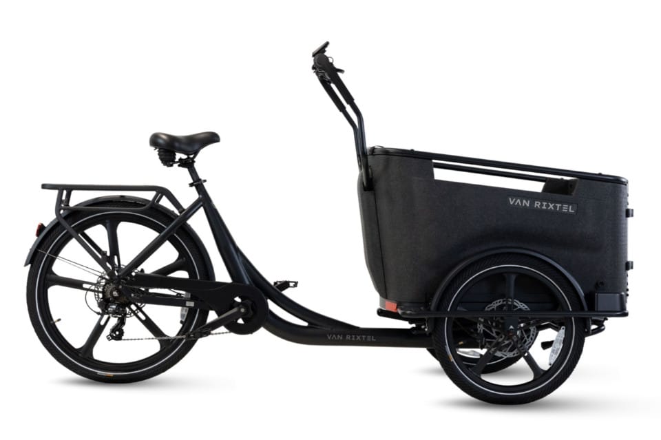 Svart trehjulig Van Rixtel Lådcykel med mittmonterad motor och remdrift, försedd med en stor förvaringslåda framtill och ett bakre pakethållare, sedd från sidan mot en vit bakgrund. Både lastlådan och cykeln är märkta med varumärket ”Van Rixtel”.