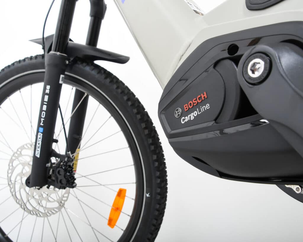 Närbild på ett framhjul från Spicy Curry x POW EZ Family Edition (2026) och en Bosch Cargo Line-motor. Däckmönstret och ekrarna sticker ut mot den vita bakgrunden och lyfter fram denna innovativa Yuba-elcykel av typen longtail.